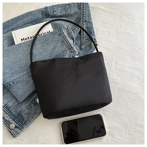Detail of black nylon bucket bag featuring embossed onwards and upwards text
