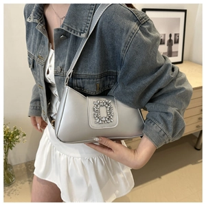 Silver baguette bag with rhinestone buckle worn as a shoulder bag on denim outfit