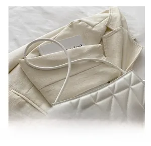Detail of white quilted leather texture and thin shoulder strap on a chic handbag