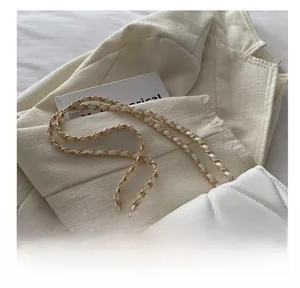 Detail showing the white quilted crossbody bag with gold metal chain strap on a blazer