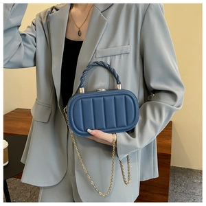 Dettaglio della borsa blu navy con trapuntatura verticale e manico a spirale dorato