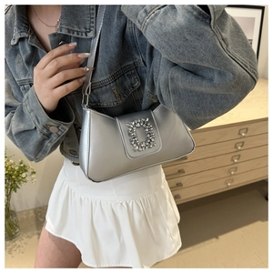Detail of silver underarm bag featuring a crystal square buckle and metallic leather texture