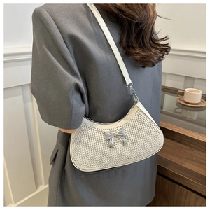 Close-up of rhinestone shoulder bag with metallic bow detail on grey blazer