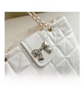 Detail of white quilted leather bag with silver butterfly clasp and chain strap