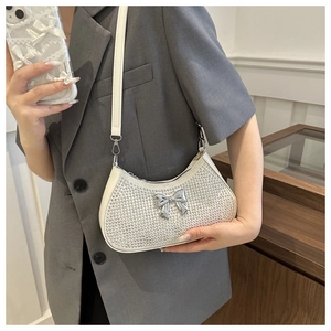Detail of white underarm bag with silver rhinestones and a metallic bow decoration