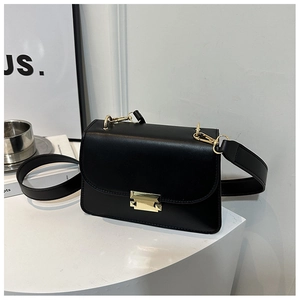 Detail of matte black leather bag featuring a gold metal buckle and wide strap