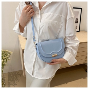 Detail of light blue PU leather saddle bag featuring a gold cylindrical metal buckle