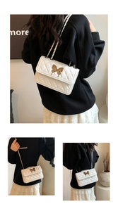Détails d'un sac bandoulière blanc matelassé avec boucle papillon dorée et chaîne