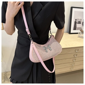 Detail of pink rhinestone shoulder bag with silver bow hardware on a black dress