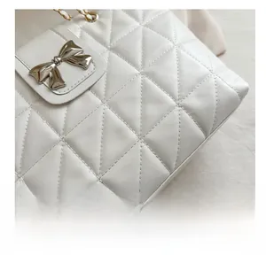 Macro shot of white quilted faux leather texture with silver bow buckle and gold chain
