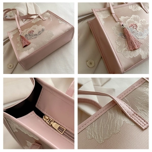 Detail view of large capacity tote bag with floral embroidery and tassel