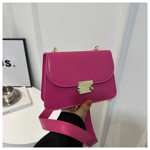 Detail of rose red leather crossbody bag featuring a sleek gold rectangular metal clasp