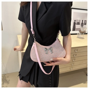 Pink rhinestone crescent shoulder bag with metallic bow detail shown on a black dress