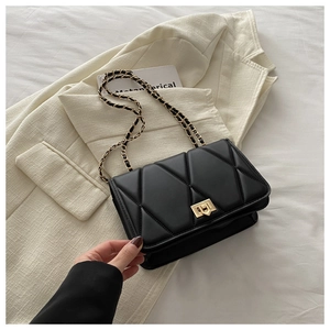 Detail of black quilted leather crossbody bag with gold chain strap and metal twist lock