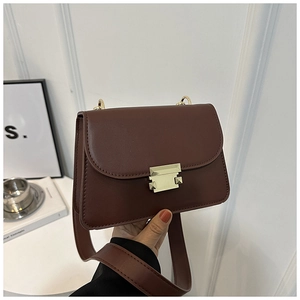 Detail view of the vintage dark brown square bag with a golden buckle and wide strap