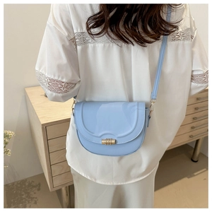 Nahaufnahme einer hellblauen Satteltasche mit goldener Schnalle an einem Modell