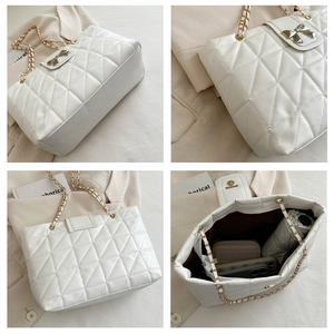 Detail of white quilted tote bag with golden chain strap and elegant bow metal clasp