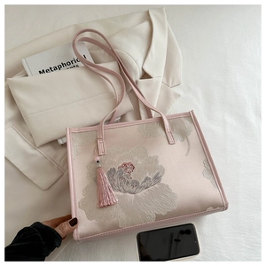 Détail du cabas en soie rose avec broderie de pivoines et pendentif à pompon en soie