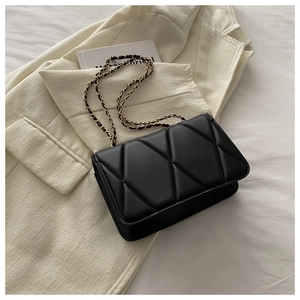 Macro shot of black quilted faux leather bag with diamond texture and chain strap