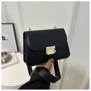 Detail of black leather square bag with gold metal buckle and wide shoulder strap