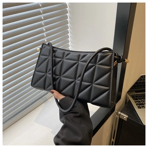 Detail of black geometric quilted handbag with gold hardware and stylish stitching