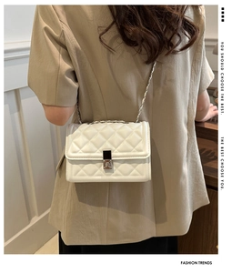 Detailed view of white quilted crossbody bag with silver chain strap and metal clasp