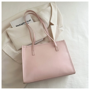 Détail d'un grand sac cabas en similicuir rose avec anses sur un blazer beige