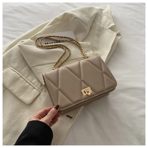 Detail of off-white quilted chain bag with gold metal twist lock and geometric patterns
