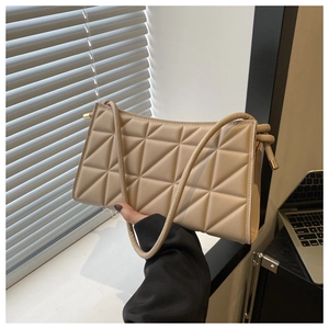 Detailed view of beige quilted leather texture and golden metal hardware on handbag
