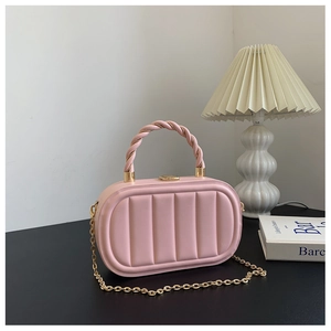 Dettaglio della borsa in pelle rosa con cuciture verticali e tracolla a catena dorata