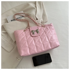 Detailed view of pink quilted tote bag with silver bow buckle and metal chain strap