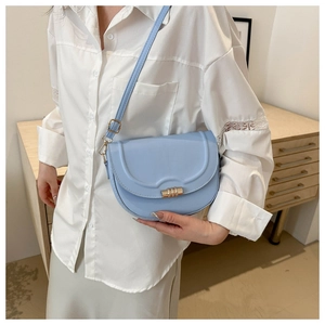 Detail of light blue saddle bag featuring a gold buckle and adjustable leather strap