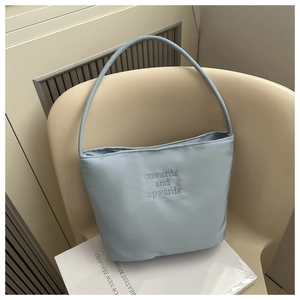 Close-up of embroidered phrase onwards and upwards on a light blue nylon tote bag