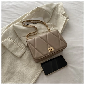 Detailed macro of beige quilted crossbody bag featuring a golden heart-shaped lock