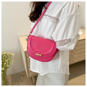 Detail of hot pink saddle bag with wavy stitching and gold clasp worn by a model