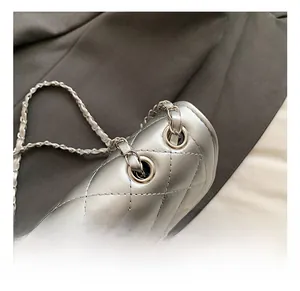 Détail du sac argenté matelassé en similicuir avec chaîne en métal poli et œillets