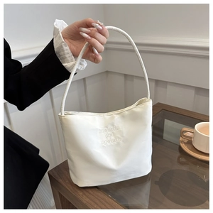 Close-up of white minimalist handbag with embossed onwards and upwards lettering detail
