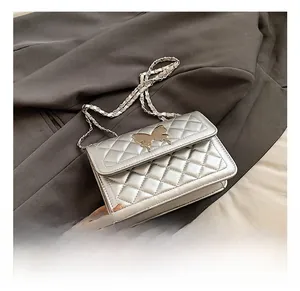 Détail du sac argenté matelassé avec fermoir papillon métallique et bandoulière chaîne