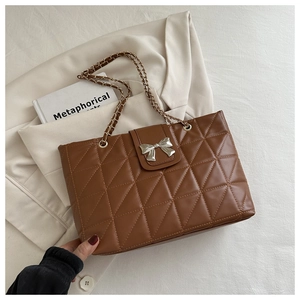 Detailed close-up of quilted rhombic pattern and golden chain strap on brown tote bag