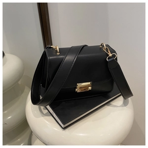 Detailed close-up of a black leather crossbody bag with a golden lock and wide strap