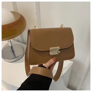 Detail of caramel leather crossbody bag with golden metal buckle and wide strap