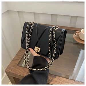 Close-up of black quilted leather shoulder bag with gold chain and rotary lock detail