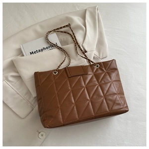 Detail of brown quilted tote bag with chain strap and elegant faux leather texture