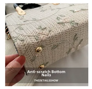 Macro detail of hand-woven bag base with floral embroidery and golden metal studs