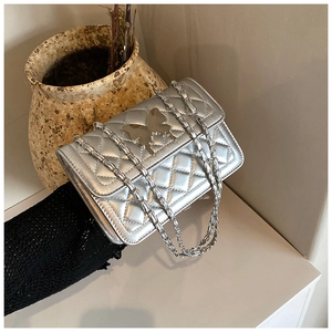 Détail du sac bandoulière argenté matelassé avec fermoir papillon et bandoulière chaîne