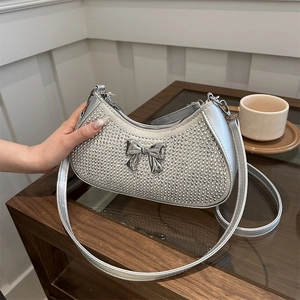 Silver rhinestone underarm bag with metal bow detail on a rustic wooden table