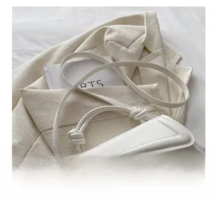 Detail of the white leather bag featuring a knotted handle and golden metal buckle