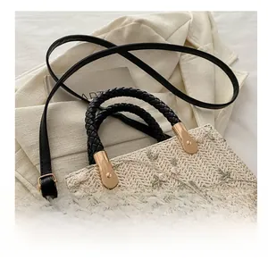 Detail showing beige woven bag with green floral embroidery and adjustable black strap