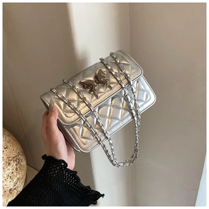 Détail du sac bandoulière argenté matelassé avec un fermoir papillon en métal brillant