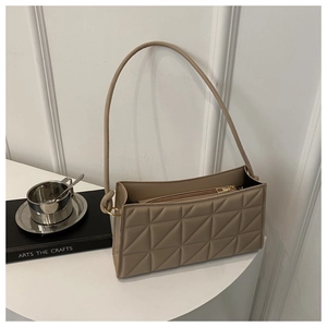 Detail of khaki square bag featuring geometric quilted texture and gold metal ring link